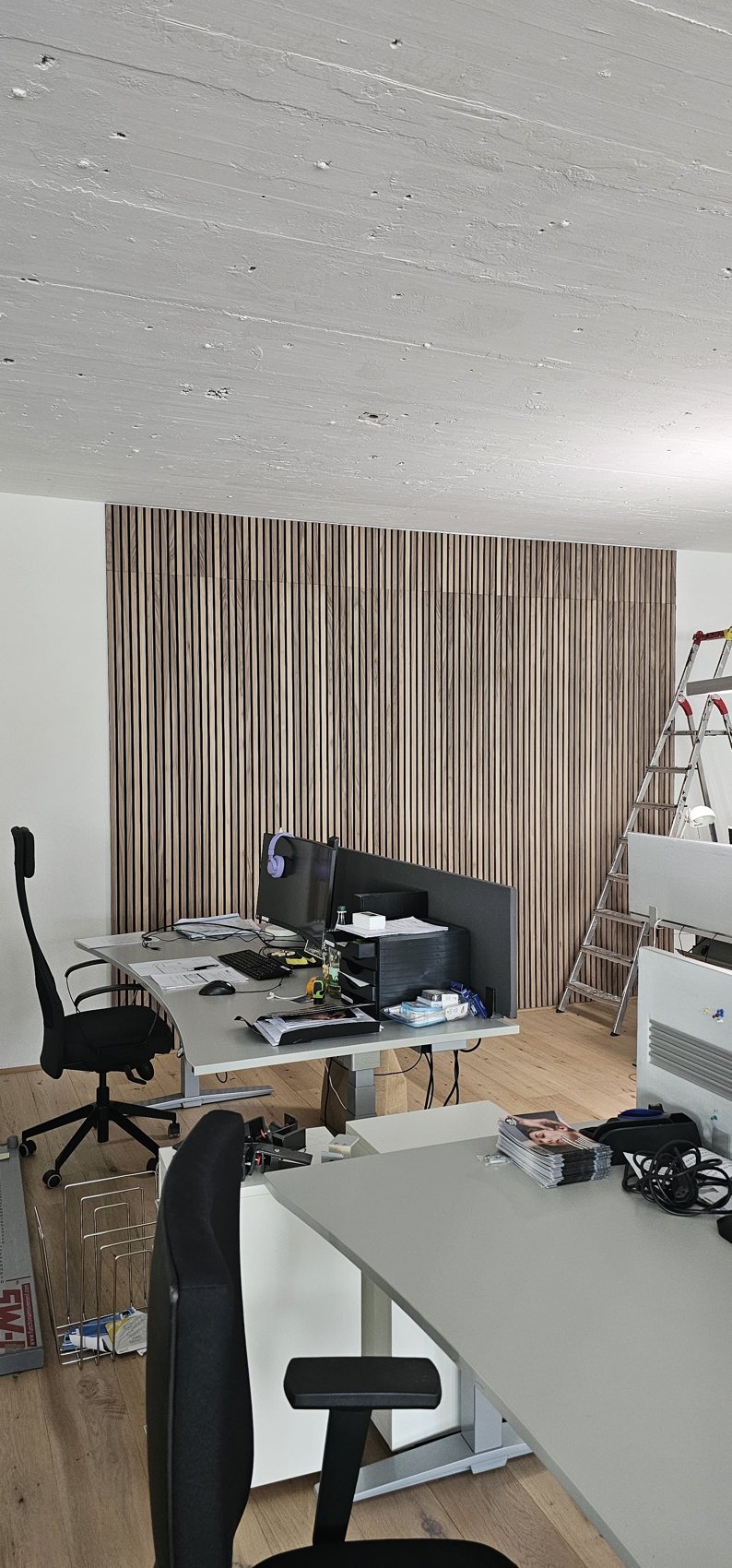 Eingerichtetes Büro mit Schreibtischen und Holzlamellenwand